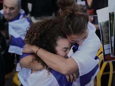 People hug in anticipation of the release of Israeli hostages held in Gaza during a gathering at a plaza known as hostages square in Tel Aviv, Israel, Monday, Oct. 13, 2025. (AP Photo/Oded Balilty)