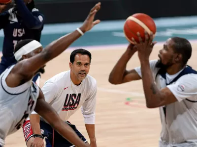 FILE - United State's Kevin Durant, right, shoots as Bam Adebayo, left, defends while assistant coach Erik Spoelstra watches during men's basketball practice at the 2024 Summer Olympics, Wednesday, July 24, 2024, in Villeneuve-d'Ascq, France. (AP Photo/Mark J. Terrill, File)