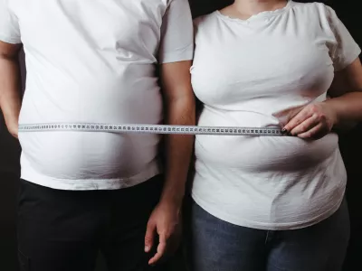 Overweight couple standing together wrapped with measure tape. Dieting, family weight loss and health care