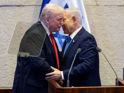 FILE PHOTO: U.S. President Donald Trump and Israeli Prime Minister Benjamin Netanyahu stand at the Knesset on the day Trump addresses it, amid a U.S.-brokered prisoner-hostage swap and ceasefire deal between Israel and Hamas, in Jerusalem, October 13, 2025. REUTERS/Evelyn Hockstein/Pool/File Photo