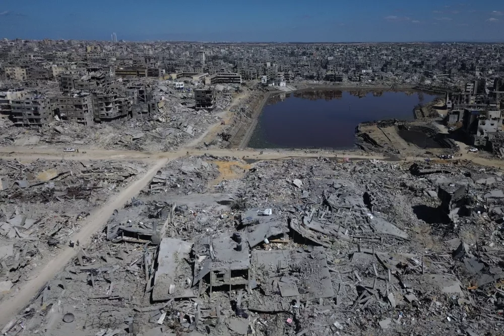 In this drone photo, Palestinians walk along streets surrounded by buildings destroyed during two years of Israeli army bombardments in Gaza City, Wednesday, Oct. 15, 2025. (AP Photo)