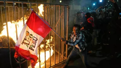 A demonstrator waves a Peruvian flag as a cardboard doll burns in front of Congress during a protest against the newly installed President Jose Jeri in Lima, Peru, Oct. 15, 2025. (AP Photo/Martin Mejia)