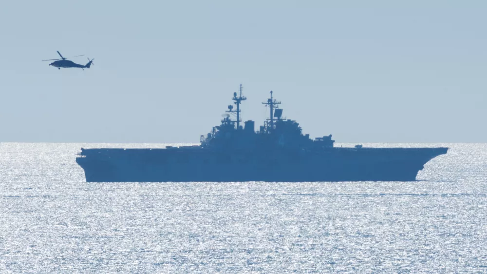 A helicopter flies past the USS Boxer (LHD 4), a Wasp-class amphibious assault ship, as it takes part in training off the coast of California near Camp Pendleton, California, U.S., October, 16, 2025.  REUTERS/Mike Blake