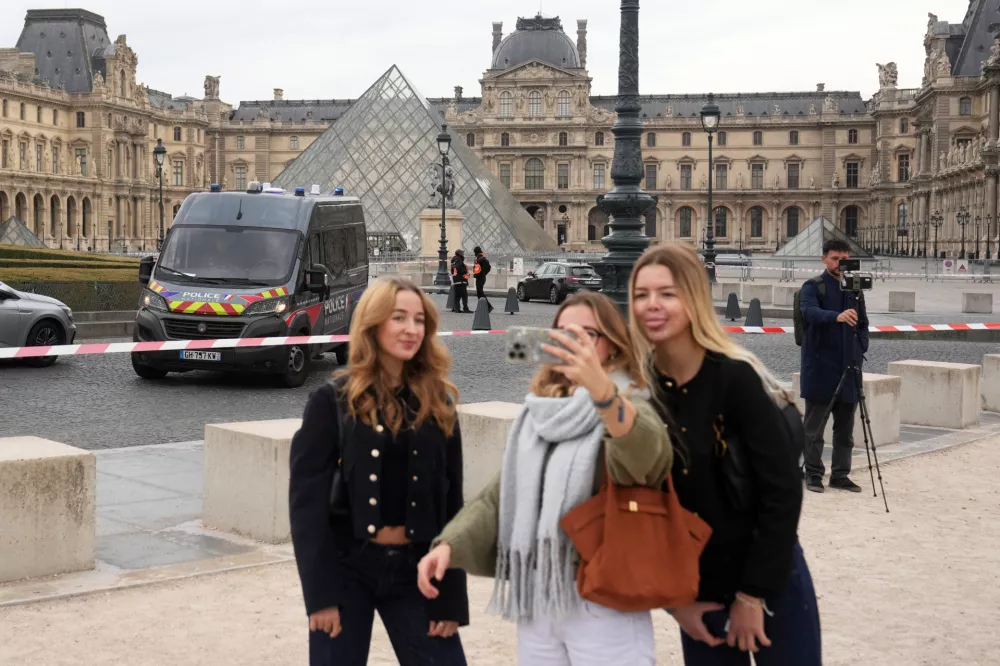 Tourists make a selfie in the courtyard of the closed Louvre museum after a robbery Sunday, Oct. 19, 2025 in Paris. (AP Photo/Thibault Camus)