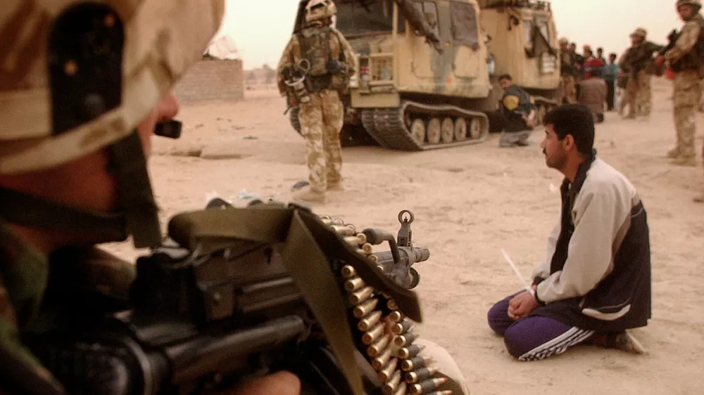 Iraški vojak pred strojnico ameriškega komandosa med invazijo leta 2003. / Foto: Profimedia