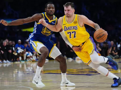 Los Angeles Lakers guard Luka Doncic (77) drives the ball against the Golden State Warriors during the second half of an NBA basketball game Tuesday, Oct. 21, 2025, in Los Angeles. (AP Photo/Ethan Swope)