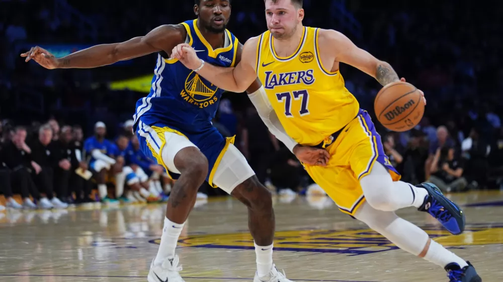 Los Angeles Lakers guard Luka Doncic (77) drives the ball against the Golden State Warriors during the second half of an NBA basketball game Tuesday, Oct. 21, 2025, in Los Angeles. (AP Photo/Ethan Swope)