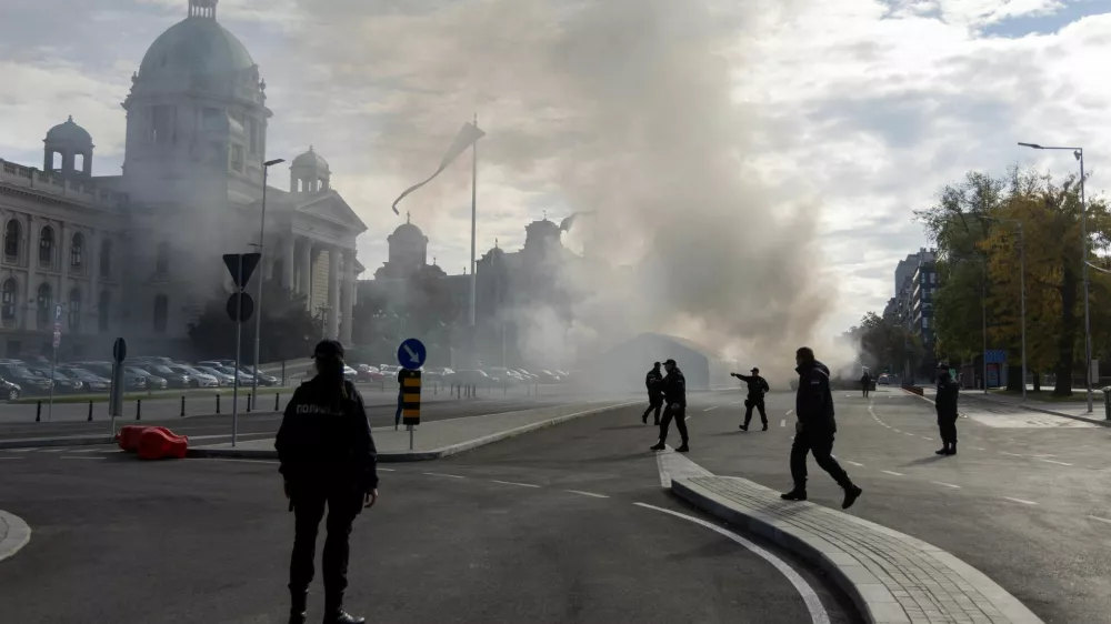 Police officers secure the area as smoke rises from a burning tent following an incident in front of the Parliament in Belgrade, Serbia, October 22, 2025. REUTERS/Djordje Kojadinovic