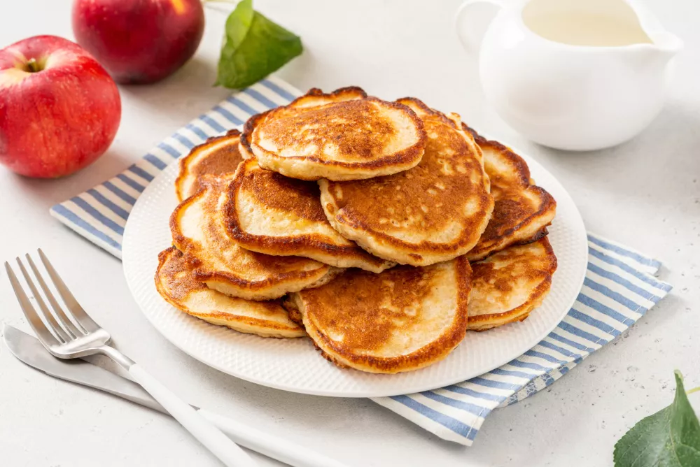 Homemade apple pancakes in a white plate on a gray concrete background. Tasty breakfast / Foto: Svetlana Monyakova