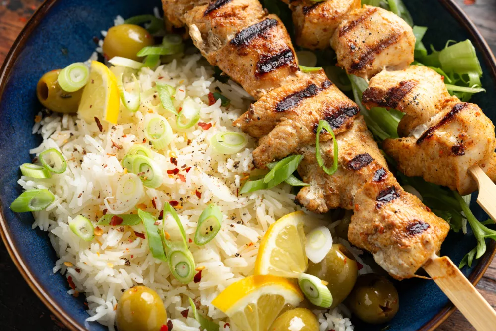 Greek grilled chicken skewers served with lemon rice and marinated green olives. / Foto: Drong