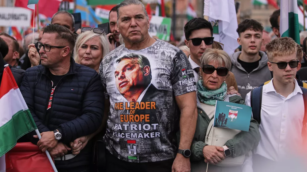 A man wearing a T-shirt with Hungarian Prime Minister Viktor Orban attends a pro-government march during celebrations marking the 69th anniversary of the outbreak of Hungary's 1956 revolution against communist rule and the Soviet Union, in Budapest, Hungary, Thursday, Oct. 23, 2025. (AP Photo/Rudolf Karancsi)