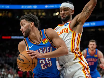 Oklahoma City Thunder guard Ajay Mitchell (25), left, drives the ball against Atlanta Hawks guard Nickeil Alexander-Walker during the first half of an NBA basketball game, Saturday, Oct. 25, 2025, in Atlanta. (AP Photo/Erik Rank)