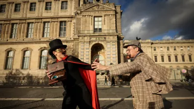 Members of the Paris Holmes Society (Cercle Holmesien de Paris), Laurence Deloision, dressed like Arsene Lupin, left, and Thierry Gilibert, dressed like Sherlok Holmes, stage the theft by the facade and the window where thieves entered the Louvre museum last Sunday, Saturday, Oct. 25, 2025 in Paris. (AP Photo/Thomas Padilla)