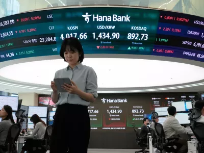 Currency traders works near a screen showing the Korea Composite Stock Price Index (KOSPI), top center left, and the foreign exchange rate between U.S. dollar and South Korean won, top center, at the foreign exchange dealing room of the Hana Bank headquarters in Seoul, South Korea, Monday, Oct. 27, 2025. (AP Photo/Ahn Young-joon)