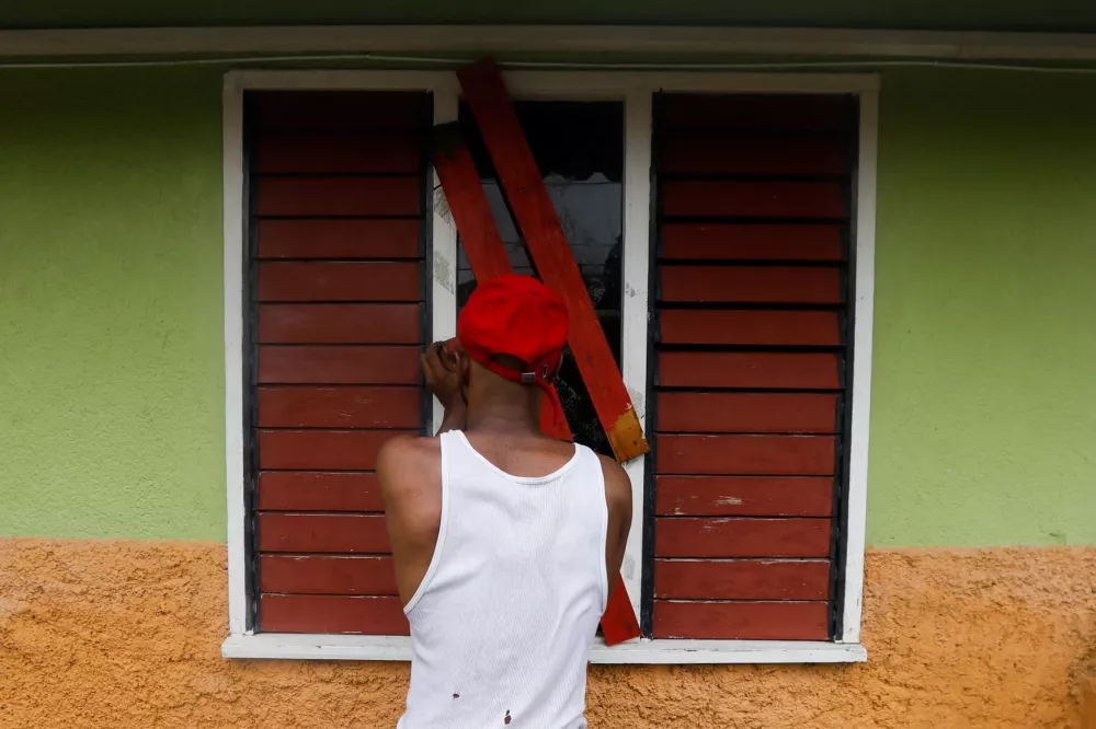 A man boards up a window, in preparation for the arrival of Hurricane Melissa, in Port Royal, Jamaica, October 26, 2025. REUTERS/Octavio Jones
