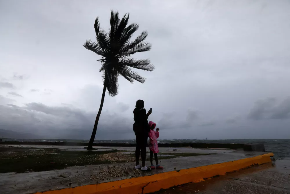 A woman and a child stand along the Kingston waterfront as Hurricane Melissa approaches, in Kingston, Jamaica, October 27, 2025. REUTERS/Octavio Jones