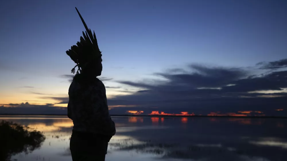 Robson Mura, of the Mura Indigenous community, watches the sunrise at the Moyray village in Autazes, Amazonas state, Brazil, Friday, Feb. 21, 2025. (AP Photo/Edmar Barros)