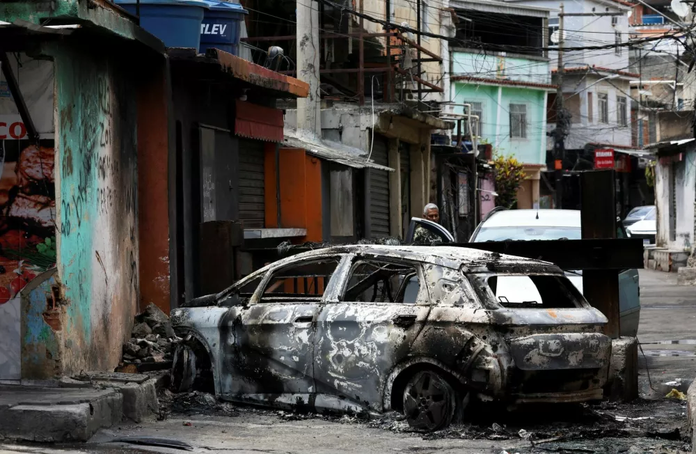 A person looks on behind a burnt car during a police operation against drug trafficking at the favela do Penha, in Rio de Janeiro, Brazil October 28, 2025. REUTERS/Aline Massuca    TPX IMAGES OF THE DAY