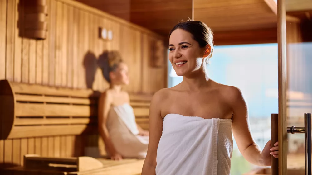 Happy woman exiting the sauna while enjoying at health spa. Copy space. / Foto: Drazen Zigic