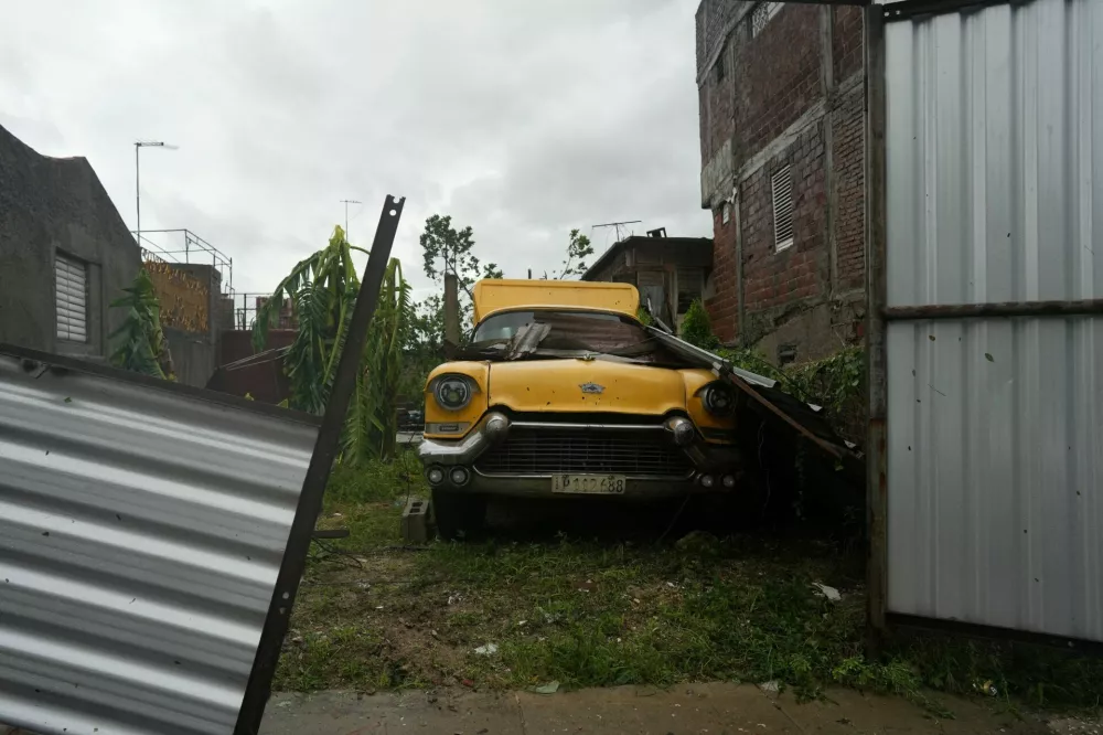 A vintage car is parked with fallen debris in the aftermath of Hurricane Melissa in Santiago, Cuba, October 29, 2025. REUTERS/Alexandre Meneghini