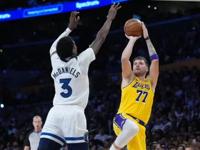 Oct 24, 2025; Los Angeles, California, USA; Los Angeles Lakers guard Luka Doncic (77) shoots the ball against Minnesota Timberwolves forward Jaden McDaniels (3) in the second half at Crypto.com Arena. Mandatory Credit: Kirby Lee-Imagn Images
