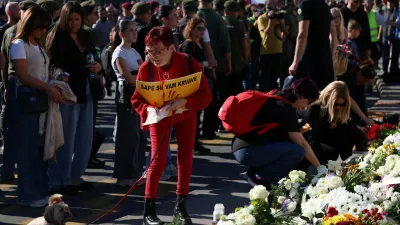 A woman holds a sign that reads: "Your paws are bloody", as people gather outside the Novi Sad railway station to pay their respects and mark the first anniversary of the fatal November 2024 railway station canopy collapse, which killed 16 people, triggering nationwide accusations of widespread corruption and negligence, in Novi Sad, Serbia, November 1, 2025. REUTERS/Zorana Jevtic