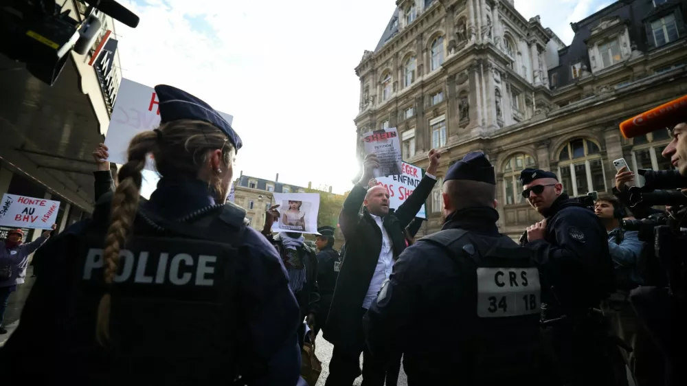 Supporters of the Association Mouv'Enfants hold placards in front of French police during a protest against the opening of the first physical space of Chinese online fast-fashion retailer Shein at the Le BHV Marais department store, the Bazar de l'Hotel de Ville, in Paris, France, November 5, 2025. REUTERS/Sarah Meyssonnier