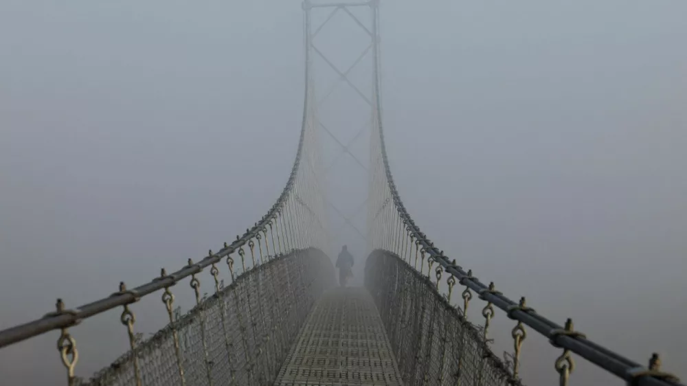 A woman walks on a suspension bridge, during a foggy morning, in Lalitpur, Nepal, November 6, 2025. REUTERS/Navesh Chitrakar   TPX IMAGES OF THE DAY / Foto: Navesh Chitrakar
