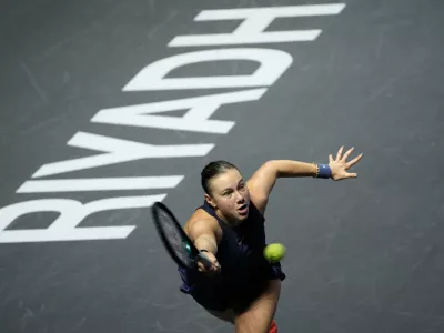 Amanda Anisimova of the United States lunges to return a ball to Iga Swiatek of Poland during their women's singles match at the WTA tennis finals in Riyadh, Saudi Arabia, Wednesday, Nov. 5, 2025. (AP Photo/Fatima Shbair)