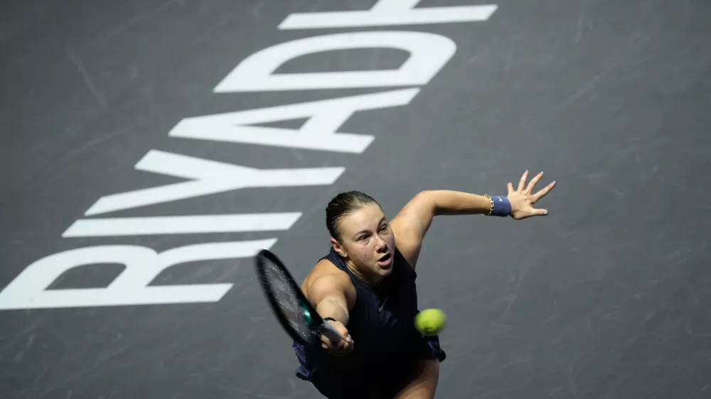Amanda Anisimova of the United States lunges to return a ball to Iga Swiatek of Poland during their women's singles match at the WTA tennis finals in Riyadh, Saudi Arabia, Wednesday, Nov. 5, 2025. (AP Photo/Fatima Shbair)