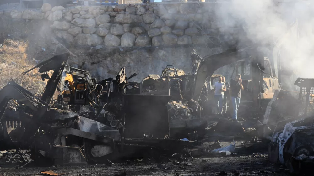 People gather at a site that sold heavy machinery, where a large number of vehicles were destroyed in Israeli airstrikes, in the southern village of Msayleh, Lebanon, Saturday, Oct. 11, 2025. (AP Photo/Mohammed Zaatari)