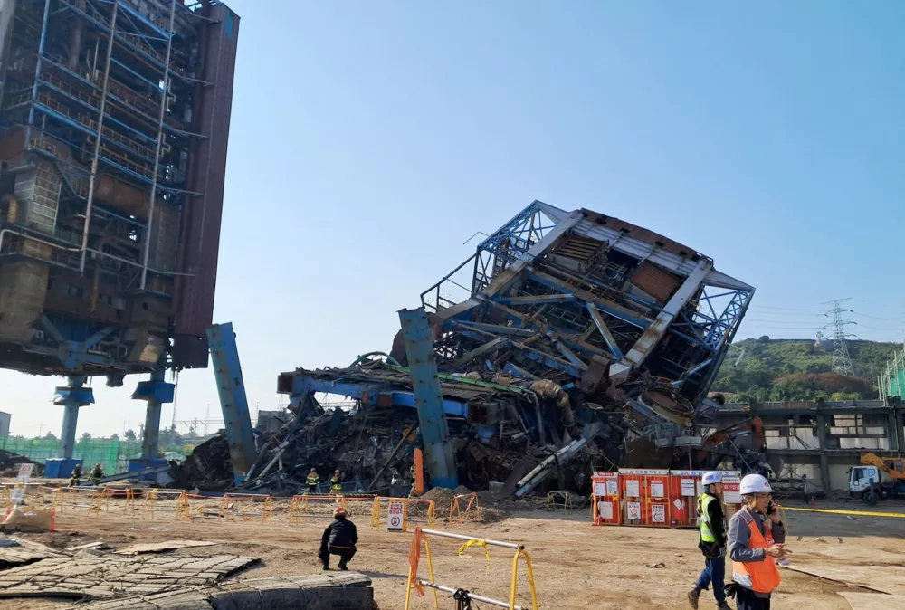 People walk near a large structure which collapsed and where multiple people are believed to be trapped, at the Korea East-West Power's Ulsan Power Plant headquarters, in Ulsan, South Korea, November 6, 2025.   Yonhap/via REUTERS    ATTENTION EDITORS - THIS IMAGE HAS BEEN SUPPLIED BY A THIRD PARTY. NO RESALES. NO ARCHIVE. SOUTH KOREA OUT. NO COMMERCIAL OR EDITORIAL SALES IN SOUTH KOREA.