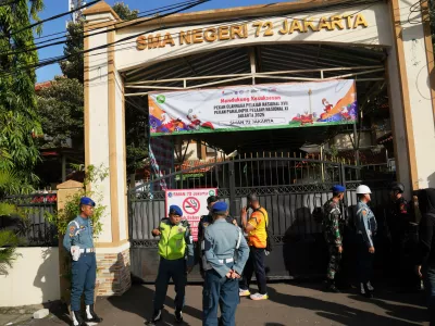 Police officers and military personnel stand guard at the gate of a school where explosions reportedly occurred, in Jakarta, Indonesia, Friday, Nov. 7, 2025. (AP Photo/Dita Alangkara)