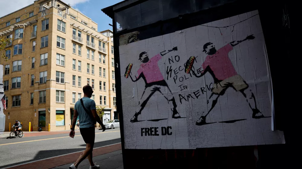FILE PHOTO: A person walks past a banner, inspired by the work of artist Banksy, showing masked protesters throwing sandwiches, weeks after U.S. President Donald Trump ordered an increased presence of federal law enforcement to assist in crime prevention, in Washington, D.C., U.S. September 11, 2025. REUTERS/Daniel Becerril/File Photo