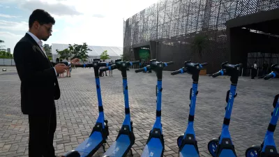 A person stands near electric scooters outside the venue of the COP30 U.N. Climate Summit, Saturday, Nov. 8, 2025, in Belem, Brazil. (AP Photo/Fernando Llano)