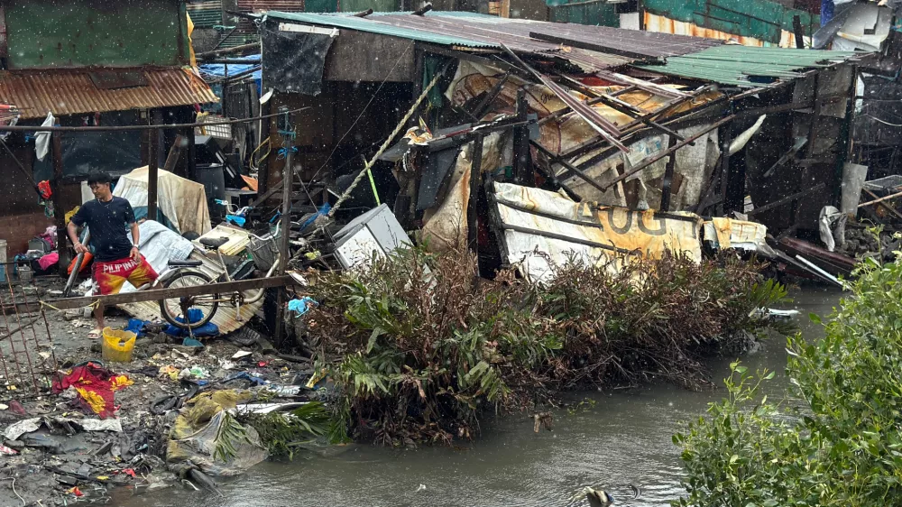 A man checks a damaged house due to Typhoon Fung-wong along a coastal village on Monday, Nov. 10, 2025, in Navotas, Philippines. (AP Photo/Aaron Favila)