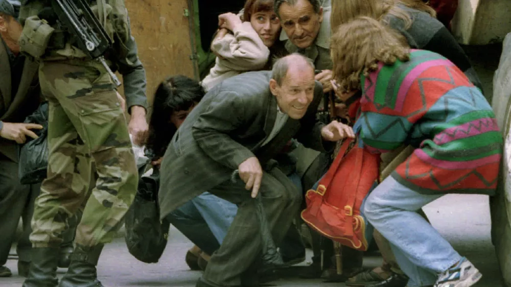 Hitchhikers, who were riding in the rear of a locked transit van which came under sniper fire in Sarajevo, take cover behind a French armoured personnel carrier after a French UN soldier (L) let them out in a June 7, 1995 file photo. Slobodan Milosevic, branded the "butcher of the Balkans" for the wars that tore Yugoslavia apart in the 1990s, was found dead in his cell on March 12, 2006 just months before his trial was expected to conclude. "Milosevic was found lifeless on his bed in his cell," the UN war crimes tribunal in The Hague said in a statement.  REUTERS/Chris Helgren/Files