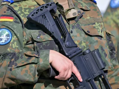 A soldier holds a weapon as he arrives during a media day at a Convoy Support Center (CSC), a logistical hub providing rest, supplies, accommodation, security services and assembly areas to support military troop movements in Germany, as Bundeswehr prepares to advance to Lithuania in the next days to attend the "Quadriga 2025" excercise, in Weisskeissel, Germany, September 6, 2025. REUTERS/Matthias Rietschell