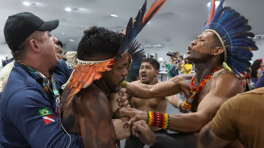An Indigenous demonstrator is held by a staff member as protesters force their way into the venue hosting the UN Climate Change Conference (COP30), in Belem, Brazil, November 11, 2025. REUTERS/Anderson Coelho   TPX IMAGES OF THE DAY