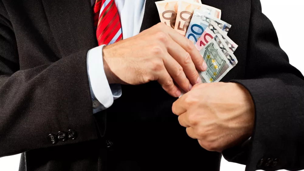Businessman putting money (euro banknotes) in his pocket.