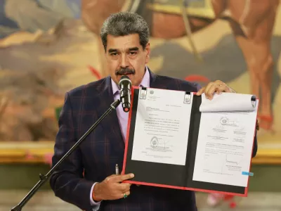 Venezuela's President Nicolas Maduro holds a folder with a national defense framework approved by Venezuela's National Assembly, ordering the immediate activation of "integral defense commands" to unify civilian and military forces, according to state television, in Caracas, Venezuela, November 11, 2025. Miraflores Palace/Handout via REUTERS ATTENTION EDITORS - THIS IMAGE HAS BEEN SUPPLIED BY A THIRD PARTY