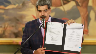 Venezuela's President Nicolas Maduro holds a folder with a national defense framework approved by Venezuela's National Assembly, ordering the immediate activation of "integral defense commands" to unify civilian and military forces, according to state television, in Caracas, Venezuela, November 11, 2025. Miraflores Palace/Handout via REUTERS ATTENTION EDITORS - THIS IMAGE HAS BEEN SUPPLIED BY A THIRD PARTY