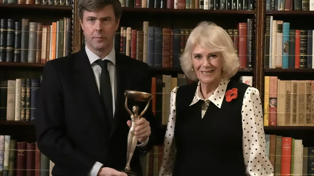 Britain's Queen Camilla poses for a photo with 2025 Booker prize winner David Szalay during a reception for shortlisted authors, judges and supporters, celebrating the Booker Prize 2025 and the newly announced Children's Booker Prize, at Clarence House in London, Britain, November 11, 2025. Stefan Rousseau/Pool via REUTERS