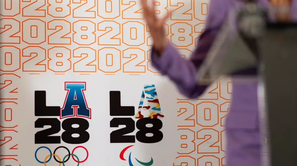FILE - LA28 logos decorate a backdrop as First lady Jill Biden speaks at a reception at the U.S. Chief of Mission Residence to commemorate the opening of the 2024 Summer Olympics and celebrate the upcoming 2028 Olympic Games, to be held in Los Angeles, Saturday, July 27, 2024, in Paris. (AP Photo/David Goldman, File)