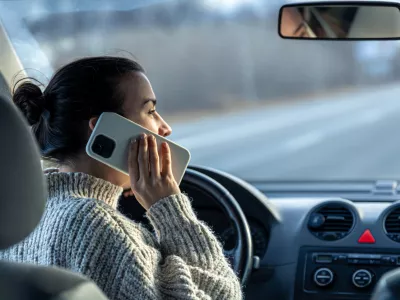 Young woman talking on the phone while driving a car, inside view. / Foto: Puhimec, Getty Images