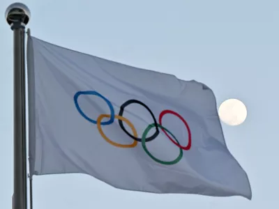 FILED - 14 February 2022, China, Beijing: The moon can be seen behind the flag with the Olympic rings. The International Olympic Committee (IOC) has agreed on a new  billion deal with long-time partners NBC for the United States broadcast rights for the 2034 and 2036 Games. Photo: Peter Kneffel/dpa