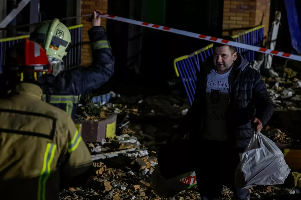 A resident of an apartment building, which was damaged during an overnight Russian drone and missile strike, carries personal belongings, amid Russia's attack on Ukraine, in Kyiv, Ukraine, November 14, 2025. REUTERS/Alina Smutko