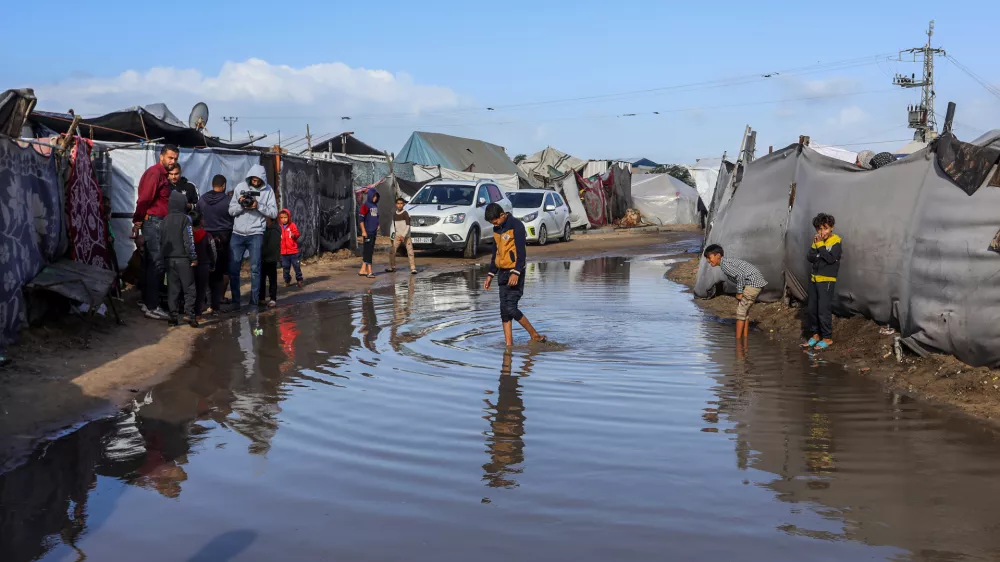 15 November 2025, Palestinian Territories, Khan Yunis: Children walk through the rainwater between their tents, as Palestinians suffer from the bitter cold and heavy rains that inundate their tents in the Al-Attar area of ··Mawasi, west of Khan Younis in the southern Gaza Strip. Photo: Abed Rahim Khatib./dpa