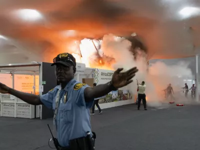 A security guard gestures as people use fire extinguishers to put out a fire at the Pavilion of Countries in the Blue Zone at the United Nations Climate Change Conference (COP30) in Belem, Brazil, November 20, 2025. REUTERS/Douglas Pingituro