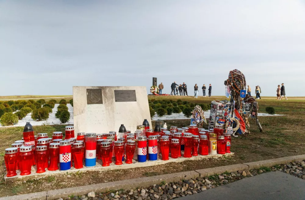 Candles are placed on the ground, as people pay respect in the background at the Ovcara mass grave site near Vukovar, Croatia, November 15, 2025. REUTERS/Antonio Bronic